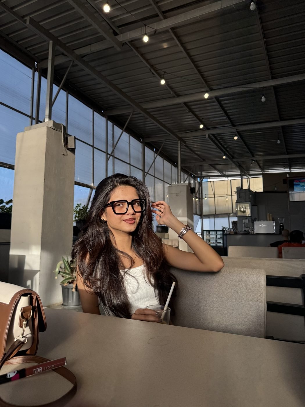 Disha Rokde in a café wearing black-framed glasses
